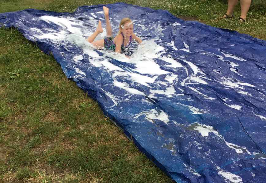 girl going down a slip and slide on her belly